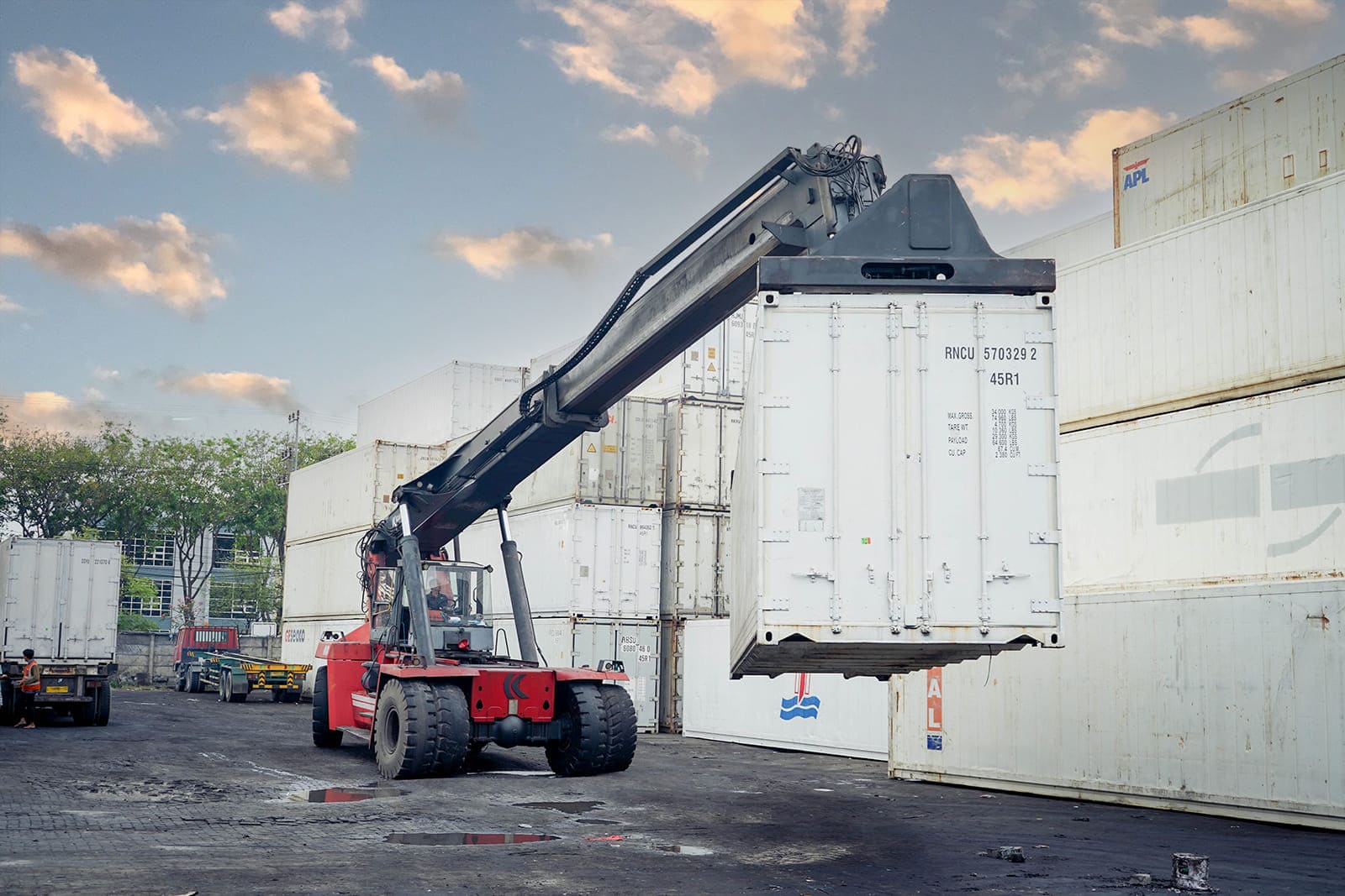 Reach stacker lifting reefer container at yard